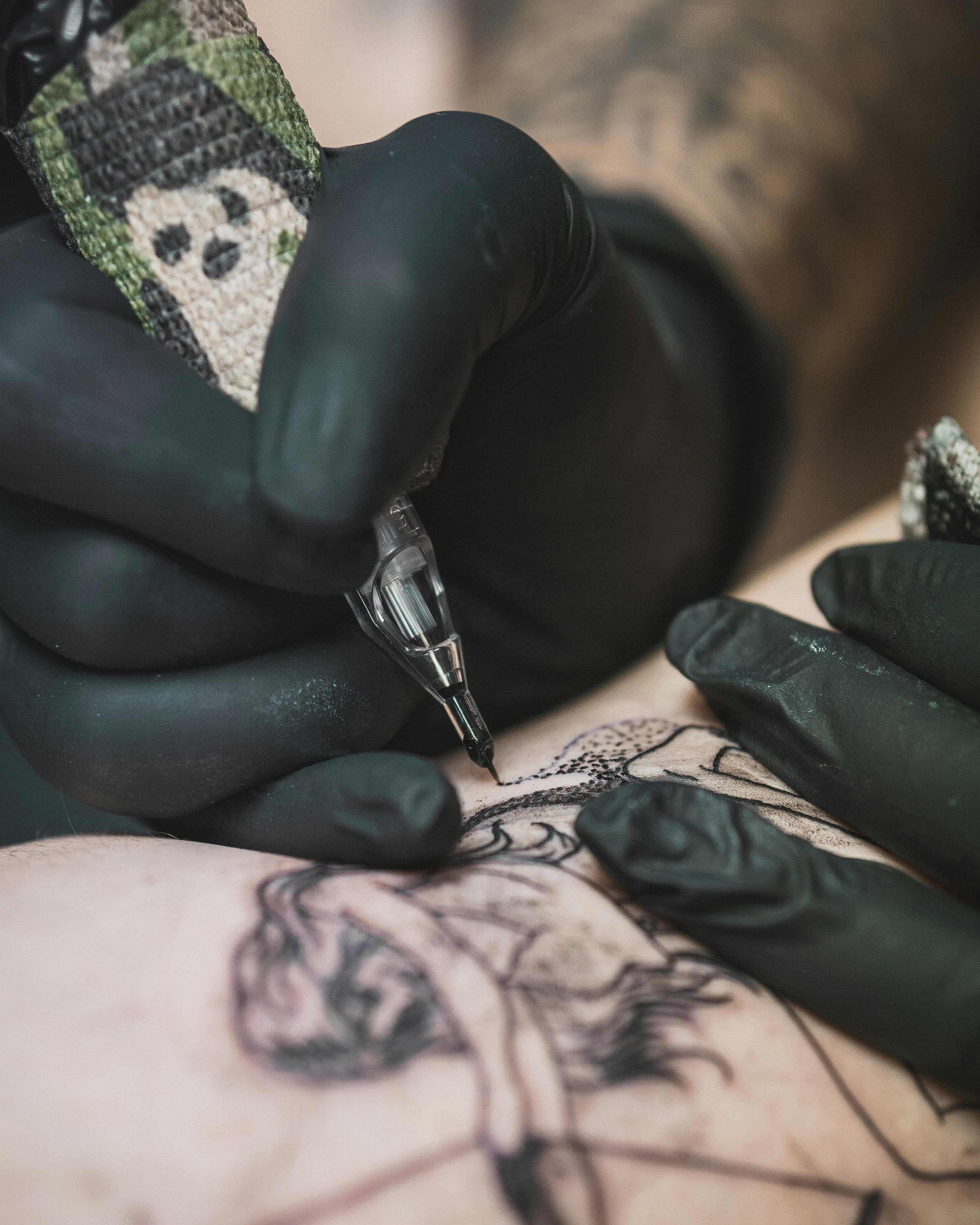 Tattoo artist creating a detailed line tattoo